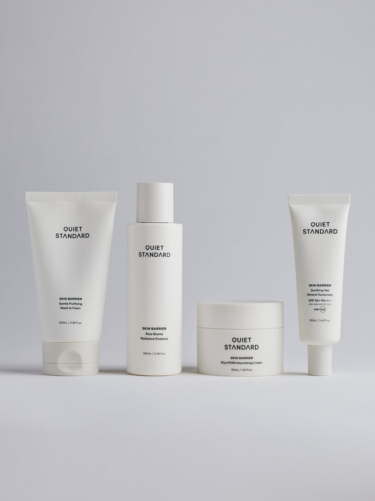 Four white skincare containers from Quiet Standard, including Gentle Purifying Mask to Foam, Rice Biome Radiance Essence, Rice PDRN Nourishing Cream, and Soothing Veil Mineral Sunscreena, arranged on a light gray background.